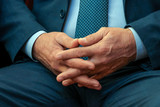 Male hands closeup. Fingers crossed among themselves. Abstract middle aged man in a suit. Concept of official or businessman in thought.