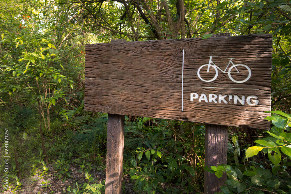 Wooden sign of a bicycle parking  green on forest background. copy space for adjust your text or message.