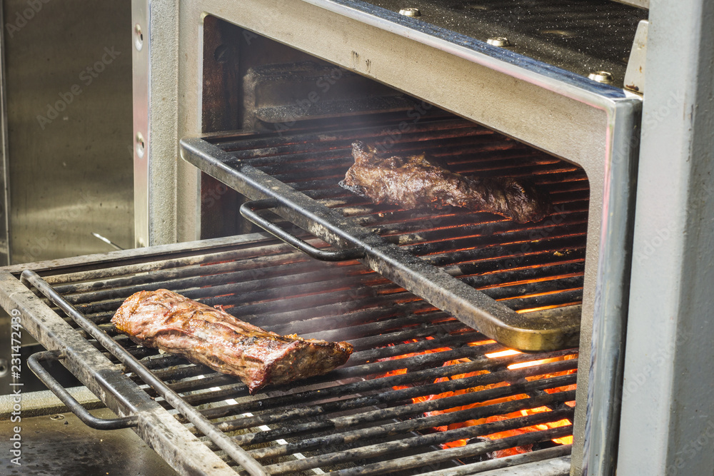 Two good pieces of meat roasts on a grill / Food shot of a beef stakes cooking on the oven with a hot coals