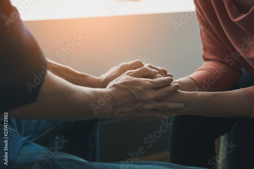 Psychologist sitting and touch hand young depressed asian woman for encouragement near window with low light environment, PTSD Mental health concept, Selective focus.