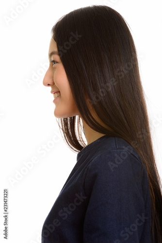 Profile view of young happy Asian teenage girl smiling