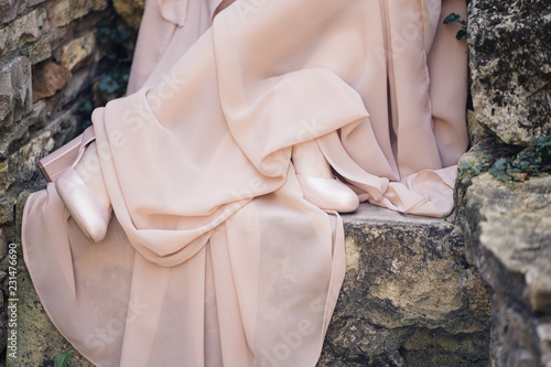 hem of pale pink dress and pink shoes on the legs of the girl