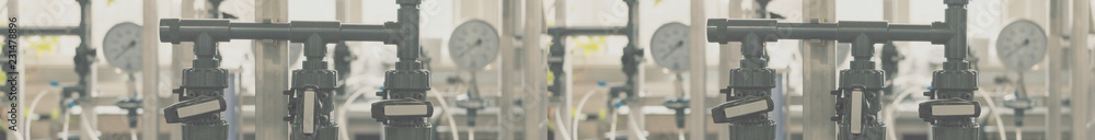 Foggy background. Closeup of process line in operation division of industrial facilities. Selective focus. Wide panoramic. Full banner length. Foggy background. Closeup of process line in operation division of industrial facilities. Selective focus. Wide panoramic. Full banner length.