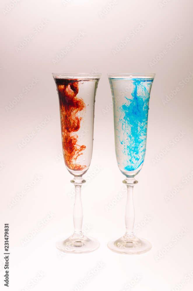 The effect of water smoke using an red and blue food coloring in two glasses for champagne on a white background. The effect of water smoke using an red and blue food coloring in two glasses for champagne on a white background.