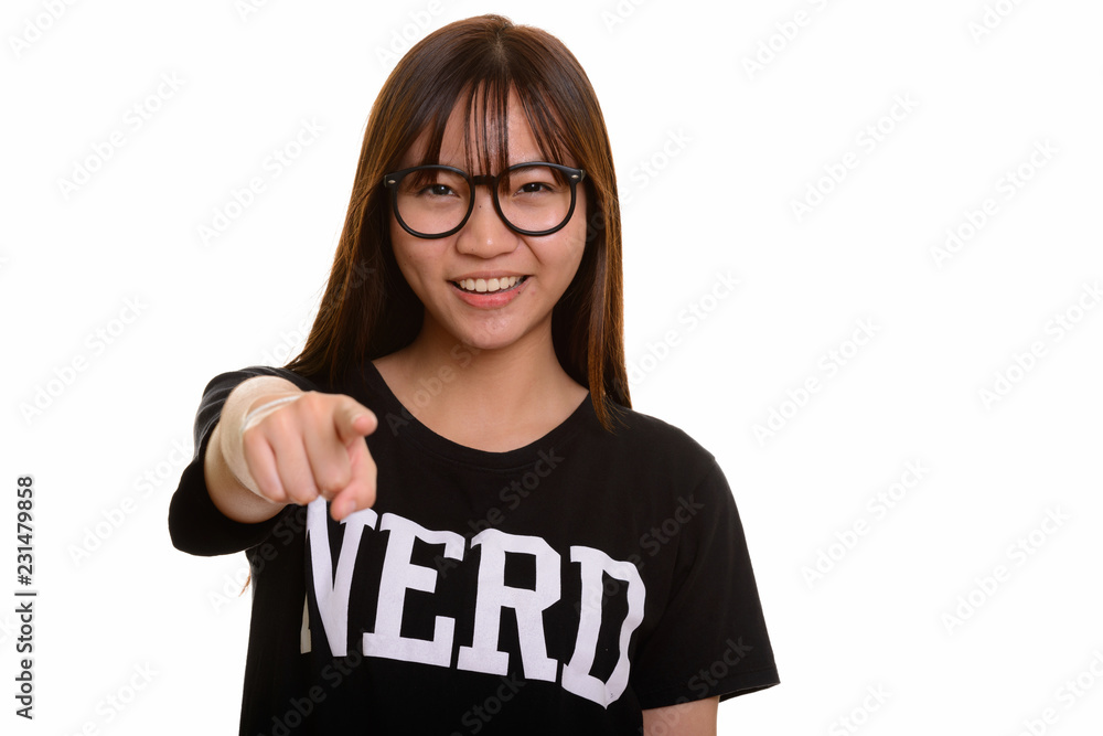 Young happy Asian nerd teenage girl smiling and pointing finger Young happy Asian nerd teenage girl smiling and pointing finger
