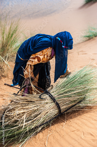 Old berber woman work alone on a sand dune in Merzouga, Morocco