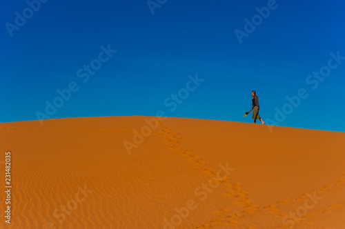 Girl walk in Erg Chebbi Desert, Sahara Desert near Merzouga, Morocco