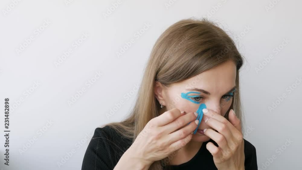 young woman doing the taping around the eyes to rejuvenate the skin and smoothing wrinkles young woman doing the taping around the eyes to rejuvenate the skin and smoothing wrinkles