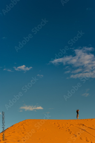 Girl stands on the dune  erg chebbi and observes the desert landscape in merzouga morocco