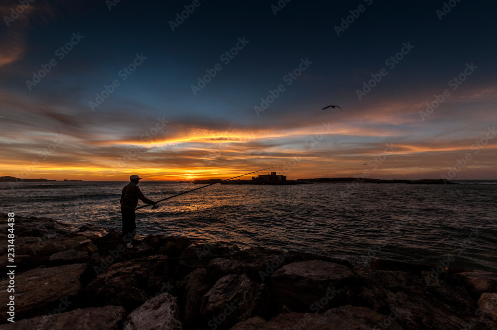 Fisherman catches fish at sunset