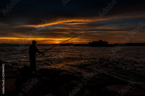 Fisherman catches fish at sunset