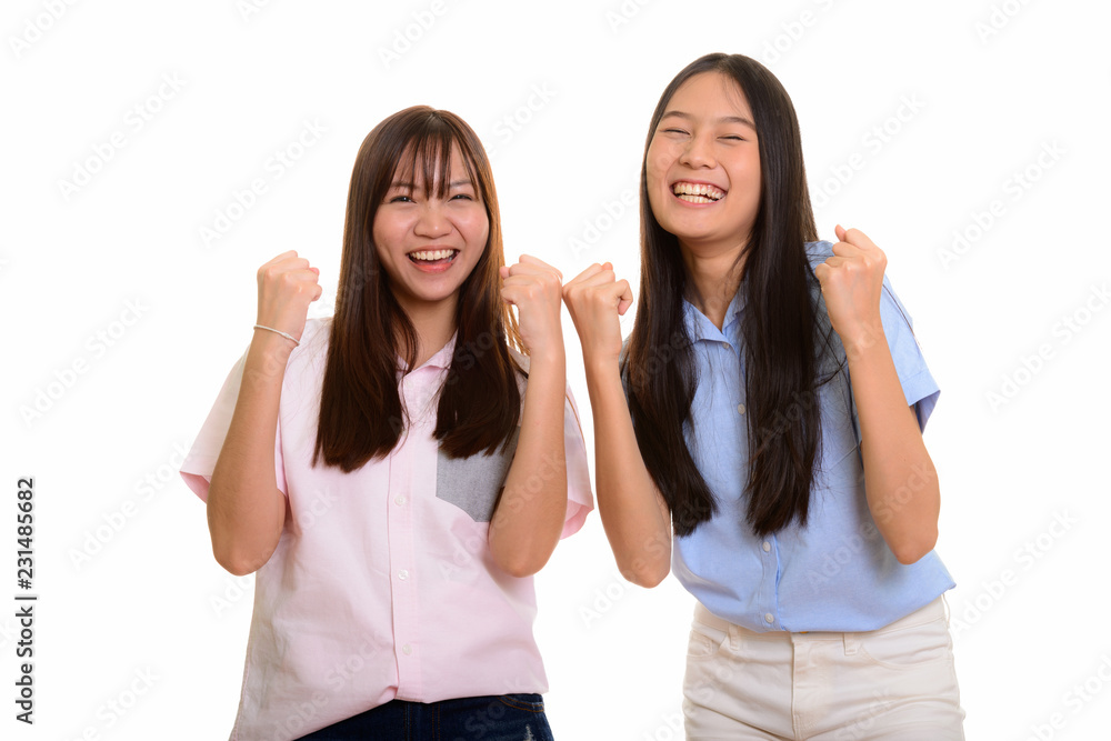 Two young happy Asian teenage girls smiling and both looking mot Two young happy Asian teenage girls smiling and both looking mot