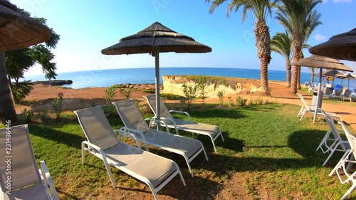 Sun loungers and sun umbrellas on sea coast. Luxury resort. Steadicam shot photo
