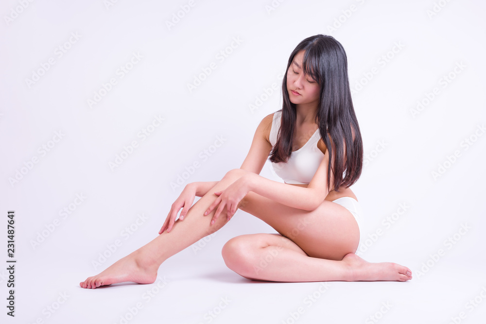 Young woman siting on white and touching leg by hands. Beauty of woman with perfect legs Young woman siting on white and touching leg by hands. Beauty of woman with perfect legs