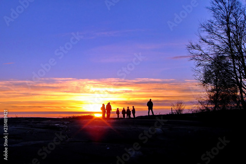 Dark silhouettes of people on winter sunset background