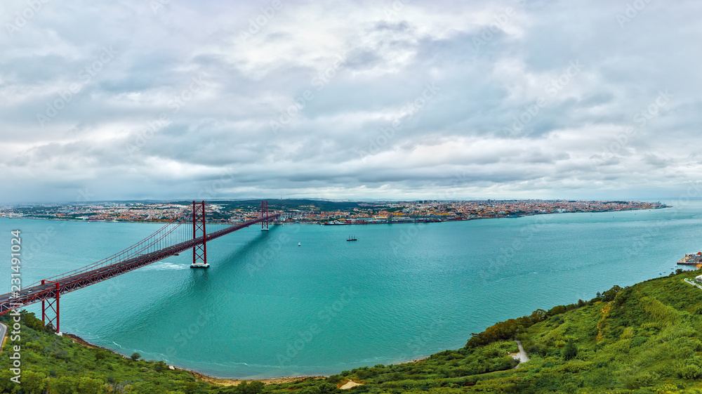 Ponte 25 de Abril Bridge in Lisbon, Portugal. Connects the cities of Lisbon and Almada crossing the Tagus River. View from Almada with Lisbon across the river. Ponte 25 de Abril Bridge in Lisbon, Portugal. Connects the cities of Lisbon and Almada crossing the Tagus River. View from Almada with Lisbon across the river.