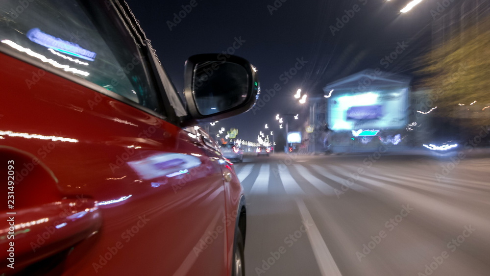 Driving urban look from fast driving car at a night avenue in a city