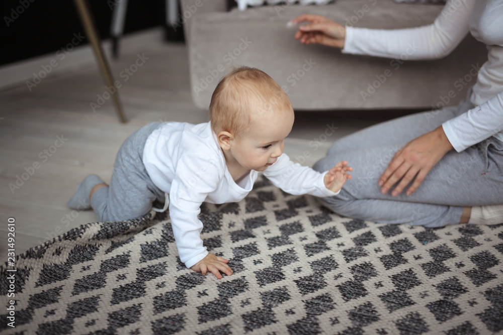 Naklejka premium Mom plays with baby in real interior communication
