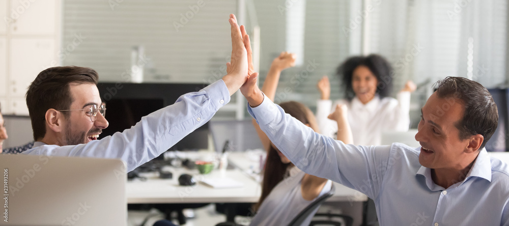 Excited euphoric male colleagues giving high five celebrating ...
