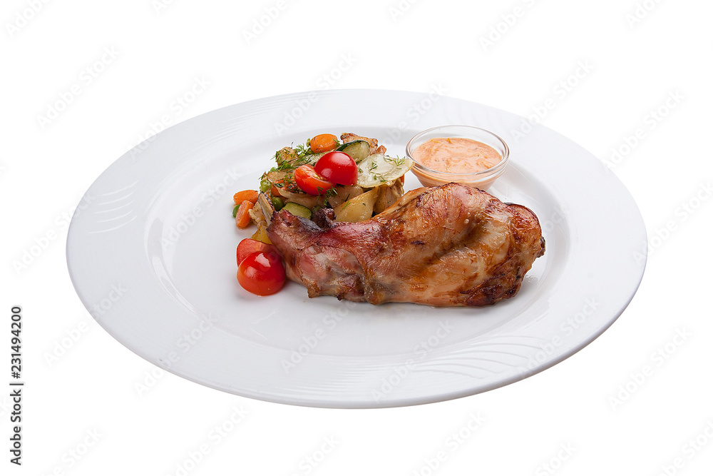 Chicken leg with baked vegetables. On a white plate