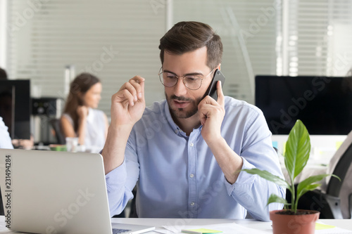 Marketing sales manager consulting client making offer selling talking on phone near laptop in office, serious business man making call negotiating speaking by mobile holding interview on cellphone photo