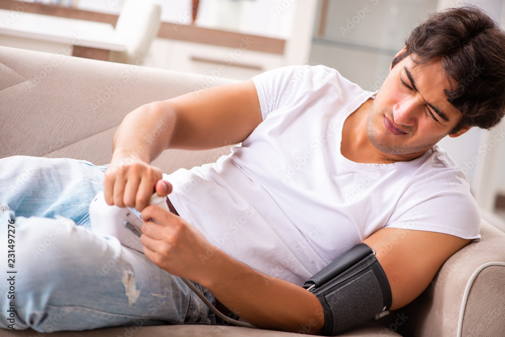Young man measuring blood pressure at home Young man measuring blood pressure at home