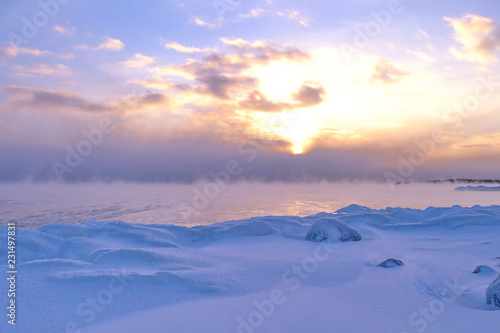 Sunset and cold fog spreads over freezing northern sea