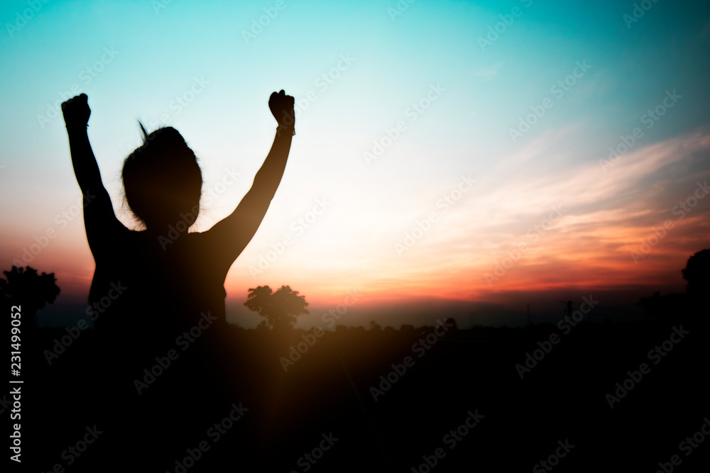 Freedom and peaceful concept, silhouette of woman relaxing and enjoying with happily in sunset