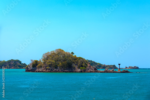 Lighthouse on the shoals of a small island on the way to the Saladan Pier bay in the bright scorching sun with turquoise green blue sea. Adaman sea, Koh Lanta, Krabi, Thailand.