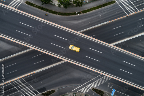 Aerial view of single car driving on highway and overpass in city