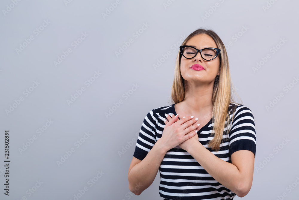 Fototapeta premium Woman with heartfelt expression on a gray background