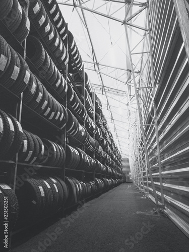 Black and white warehouse fully stacked with car tyres.
