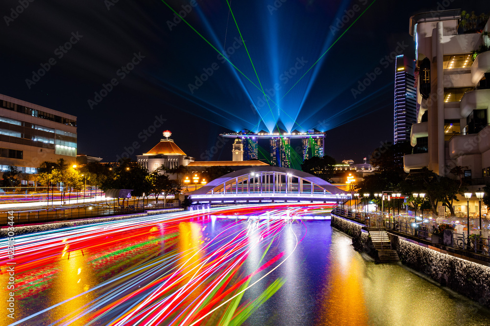 Singapore skyscrapers and passenger boat light trails at night