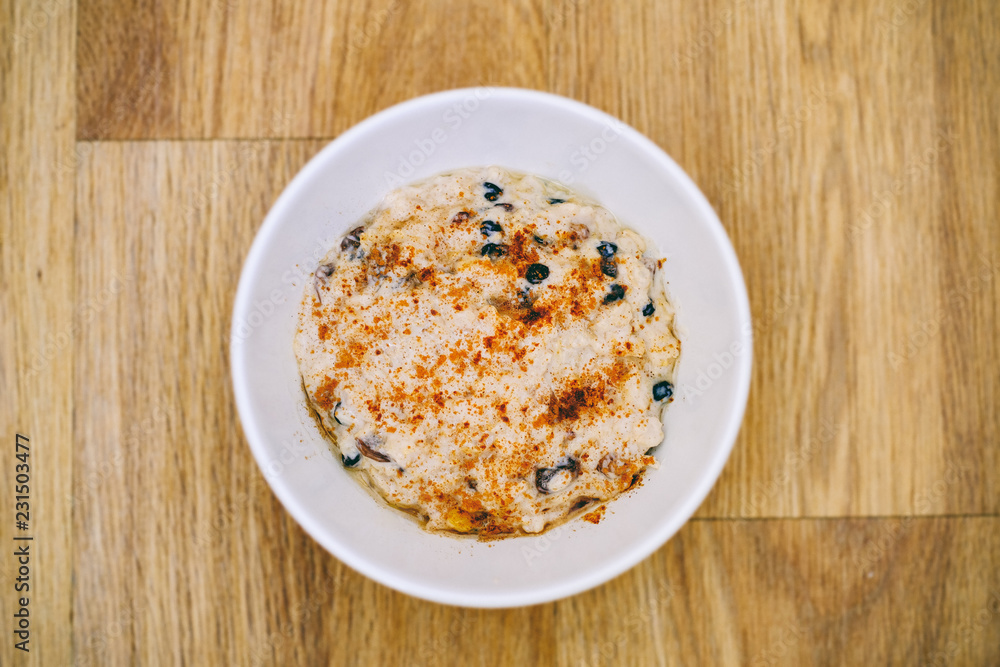 Breakfast porridge in a white bowl with raisins and cinnamon Breakfast porridge in a white bowl with raisins and cinnamon