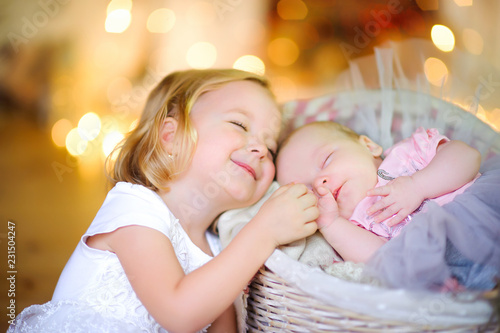 Obraz na płótnie girl holds her hand and gently snuggles up to her little sister, amid bright lights w salonie