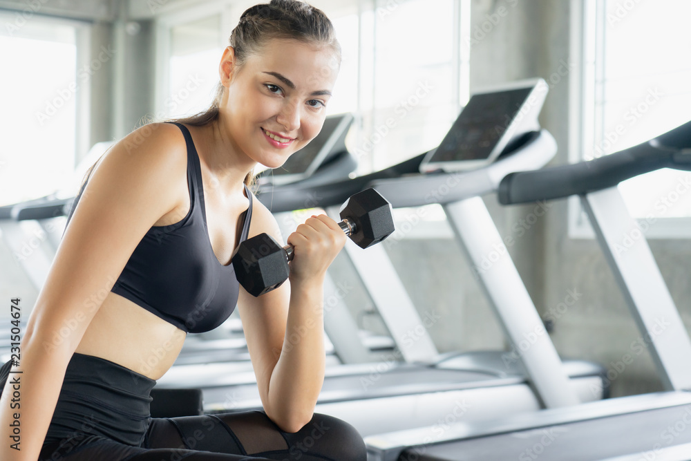 Muscular young woman with beautiful body doing exercises with dumbbell. Sporty girl lifting weights in gym. Muscular young woman with beautiful body doing exercises with dumbbell. Sporty girl lifting weights in gym.