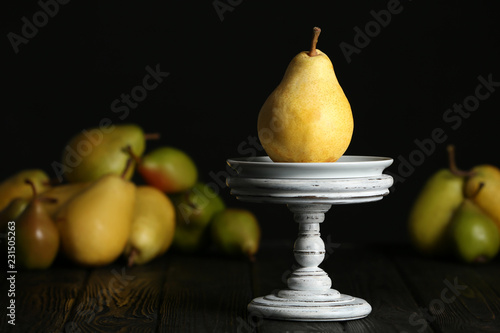 Stand with fresh ripe pear on table against blurred background