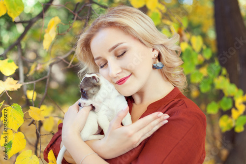 Young woman with a puppy in autumn park.