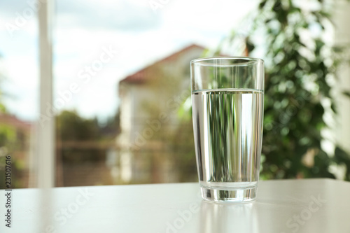 Glass of fresh water on table indoors. Space for text