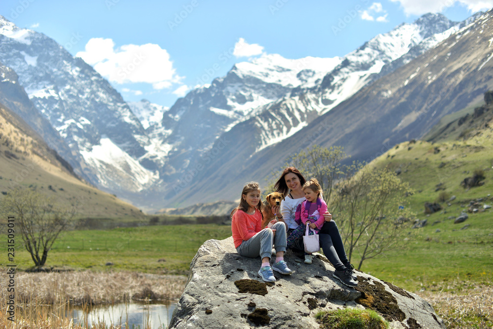 Happy family with a dog resting in nature in the mountains