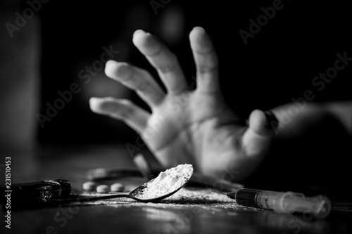International Day against Drug Abuse. Young human hand trying to reach cooked heroin spoon on grungy concrete floor. Drugs addiction and withdrawal symptoms concept. Copy space.