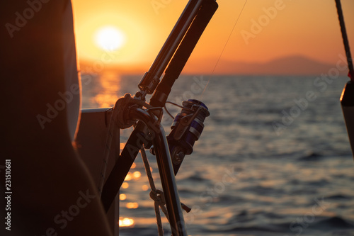 Boat fishing rods over a beautiful sunset seascape horizontal