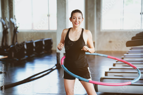 Beautiful Asian women wearing sportswear. Playing hula hoop in the morning gym. Helps to burn excess fat in body. Strengthens the muscles of the body. Increases blood flow to the brain. Good health