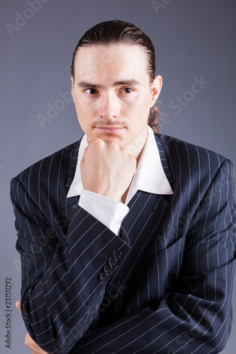 Portrait young man, holding arm with fist on chin, concentrated and looking at camera, isolated on grey background © shanshinyury