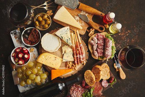 Huge assortment of various tasety spanish, french or italian apertizers. Cheese, meat, olives, stuffed peppers, bread, sticks. Placed on rusty dark background. View from above.