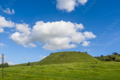 The west side of Wolstonbury Hill in the South Downs National Park in the county of Sussex UK on a sunny day with cumulus clouds rising above the hill.