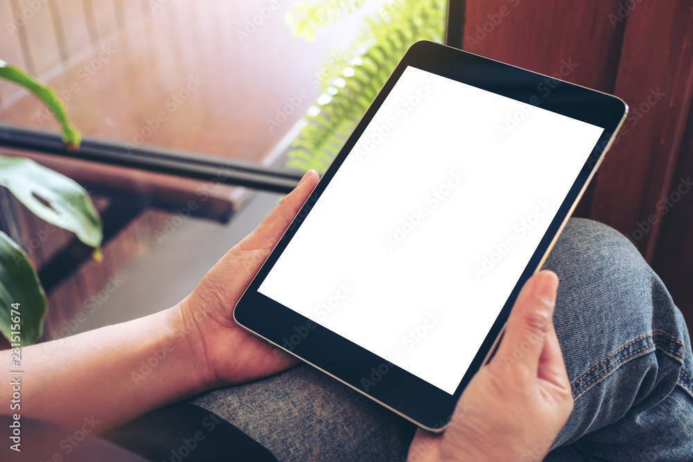 Mockup image of a woman holding black tablet pc with blank white screen while sitting in cafe Mockup image of a woman holding black tablet pc with blank white screen while sitting in cafe