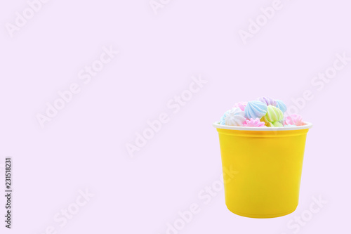 Meringues It is a Swiss and French dessert in the yellow plastic cup isolated on purple pastel background.