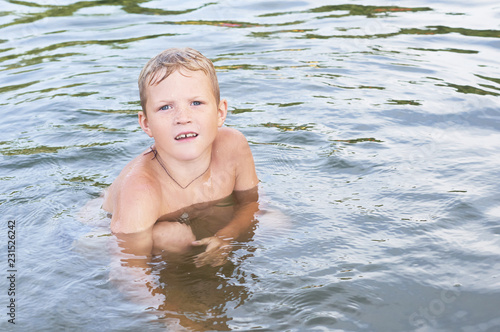 Portrait of happy fun little Caucasian boy swimming in the sea or lake.