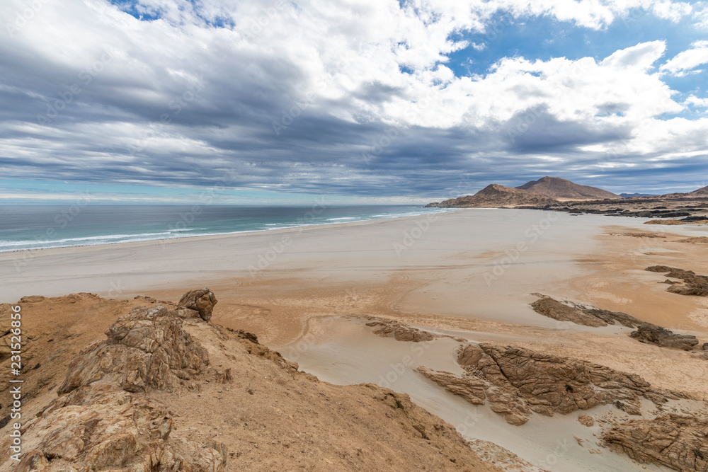 An idyllic beach at a remote location inside an arid landscape at Atacama Desert coast. The waves coming from the Pacific Ocean crash the rocks of the desert on an amazing wild dry scenery
